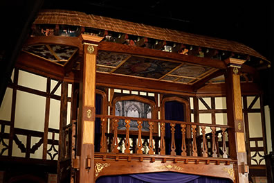 Photo by Will Kirk Photography of the tiring house balcony with a ceiling of painted images under a tiled roof.