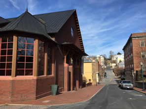 The Blackfriars Playhouse all in brick, a bay window beside and a peaked roof above the main entrance with a view of the street heading beyond to Mary Baldwin College