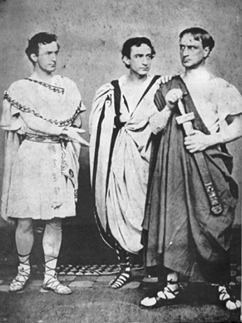 Black-and-white portrait from 1864 of the booth brothers in ancient Roman costum, with John Wilkes Booth's Marc ANtory holding his hand out toward Junius Brutus Booth Jr.'s Cassius, who has his hand on his sword hilt