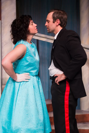 Beatrice in blue party dress and white gloves, Benedick in black uniform with red piping on the pants, both facing each other nose to nose with hands on hips.