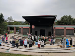 Photo of audience members standing for cast at amphitheater